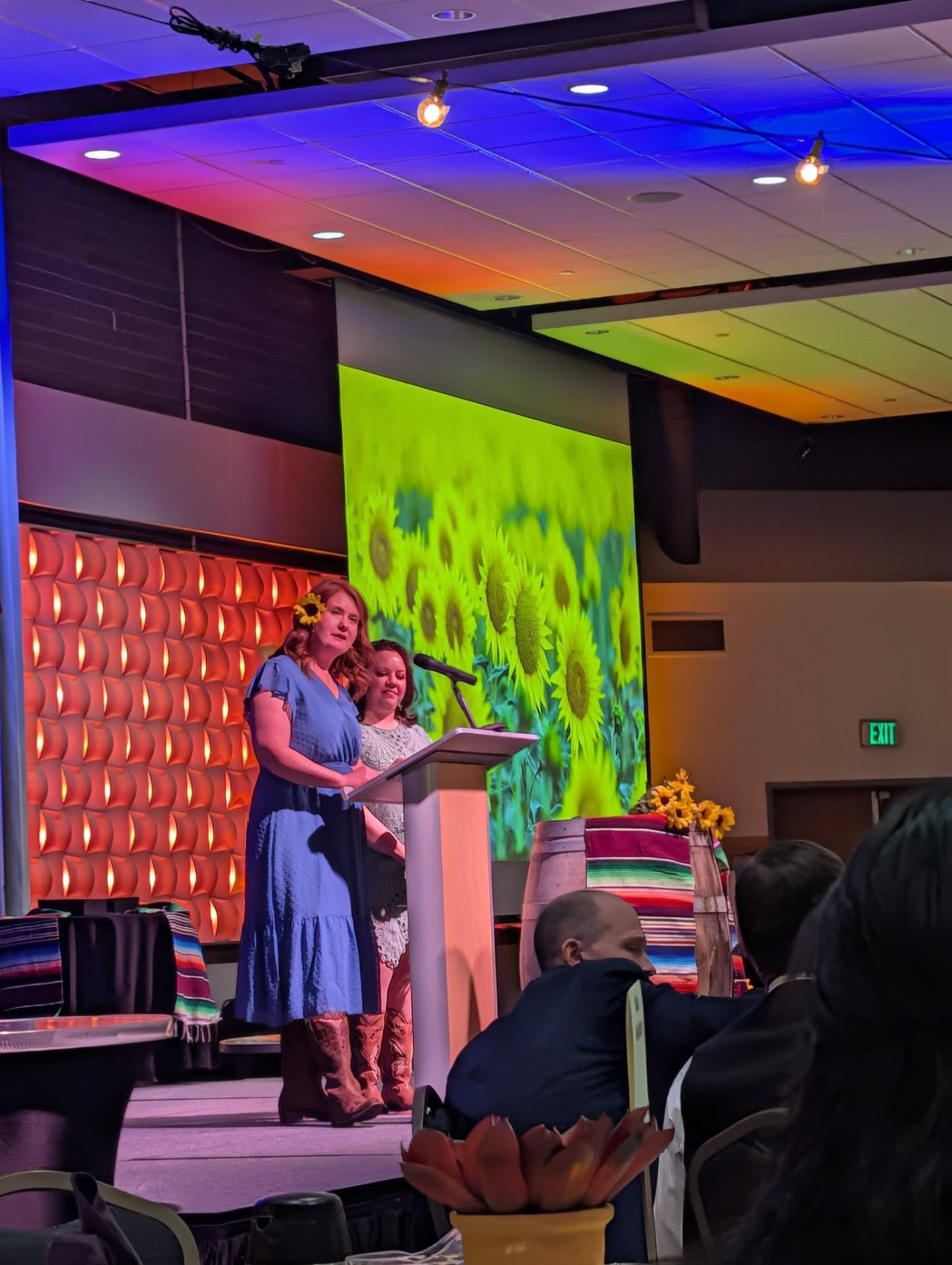 Speaking at a nonprofit gala podium with sunflowers